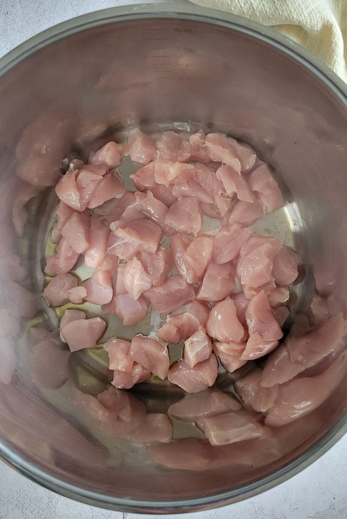 raw chicken chunks cooking in oil in a pot