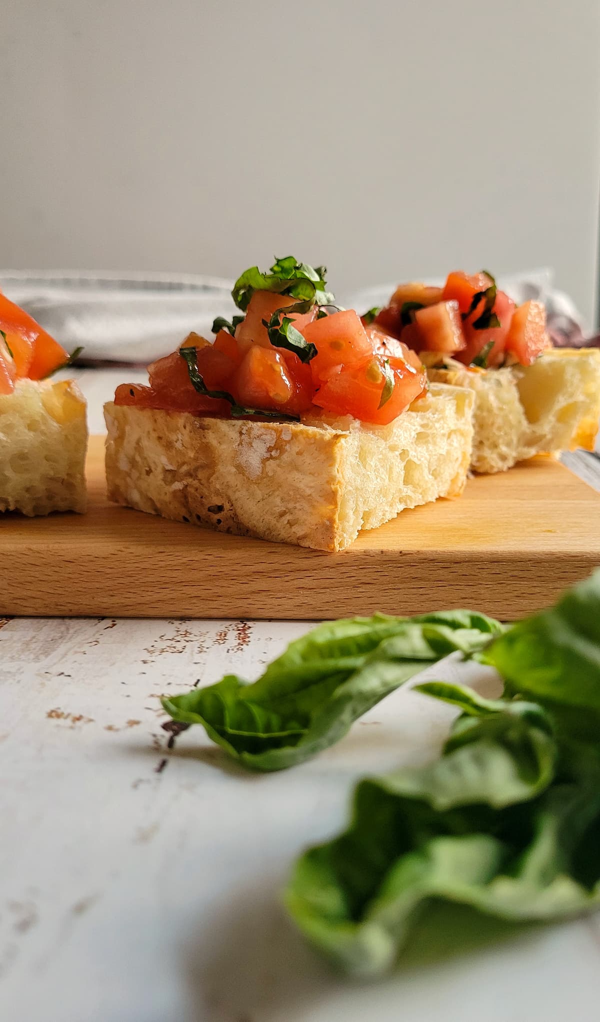 pieces of bruschetta topped with fresh chopped basil on a cutting board