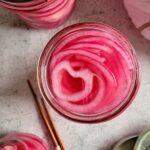 jars of pickled red onions next to chopsticks