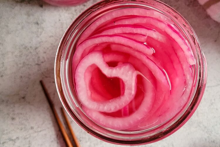 jars of pickled red onions next to chopsticks