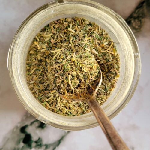 homemade italian seasoning in a jar with a spoon