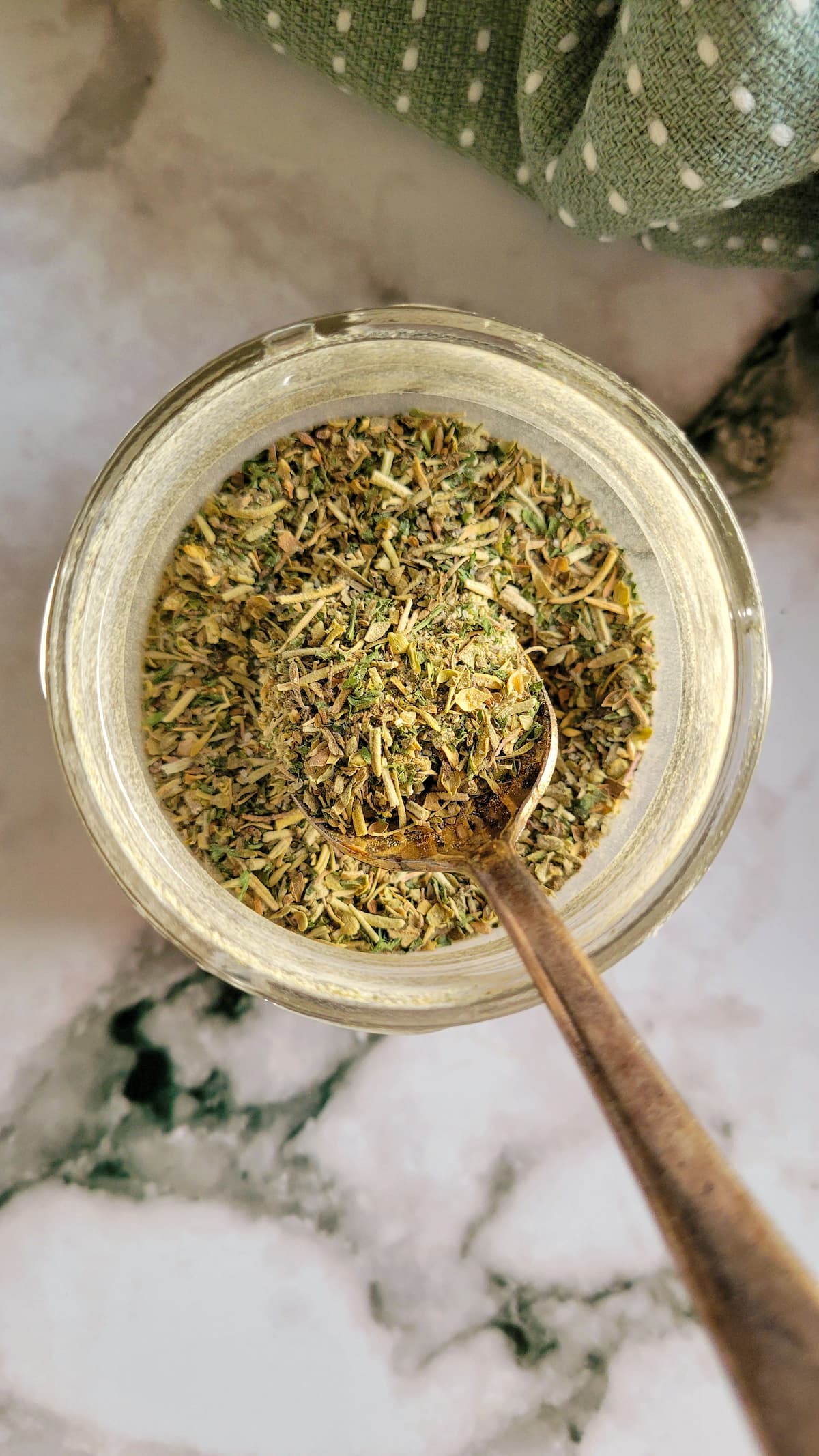 homemade italian seasoning in a jar with a spoon