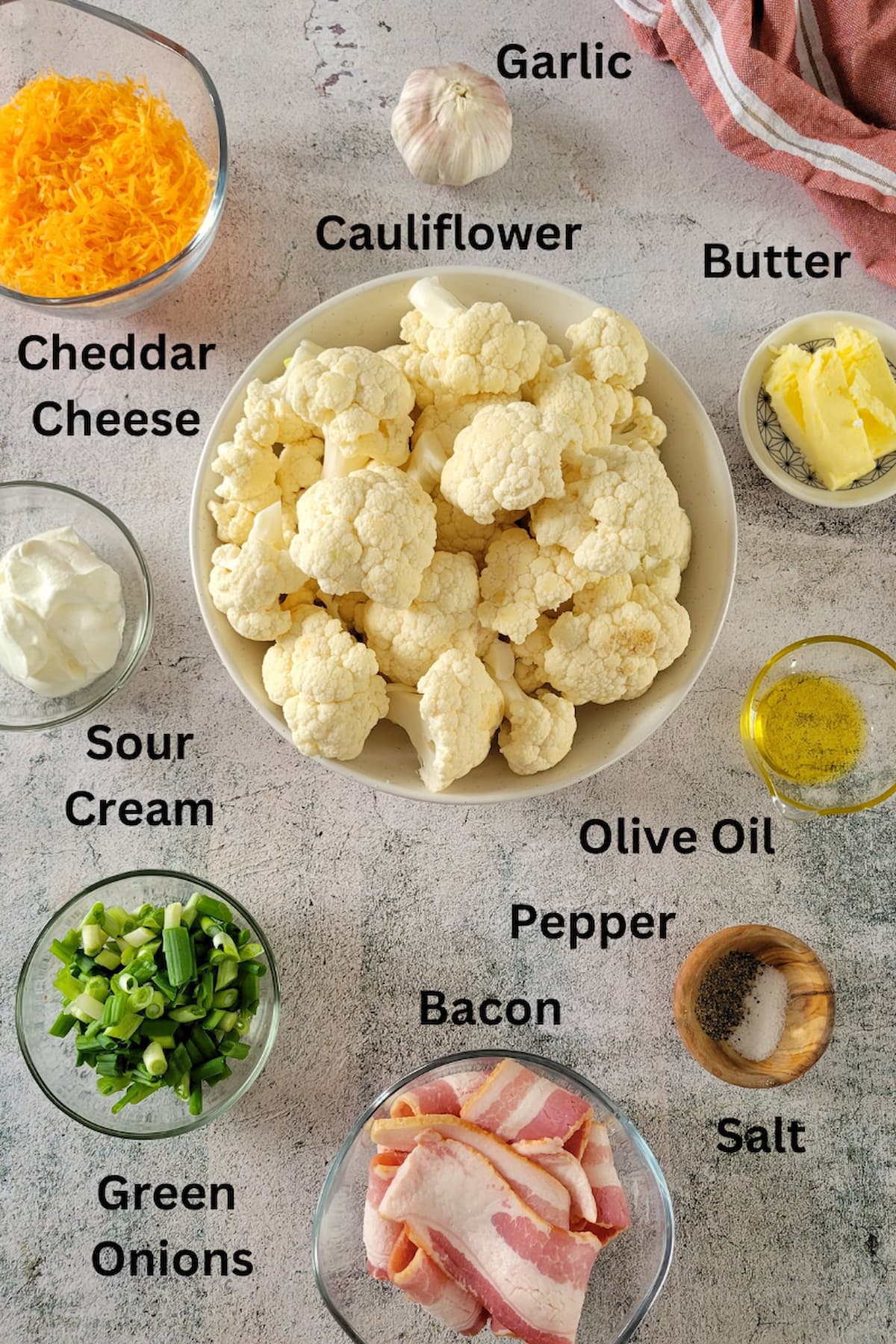 ingredients for mashed cauliflower recipe - garlic, salt, pepper, cauliflower, bacon, green onions, butter, cheddar cheese, sour cream, olive oil