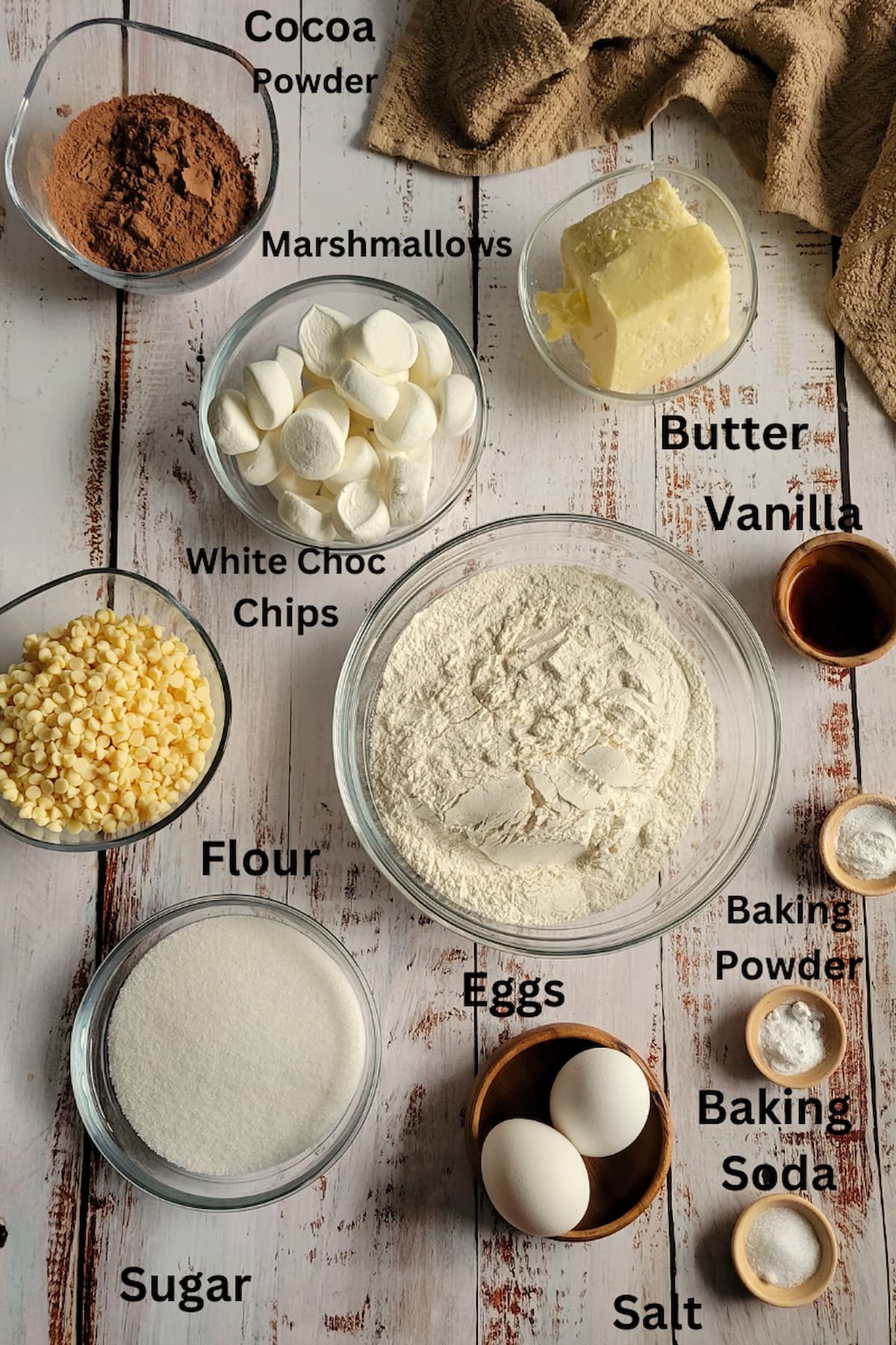 ingredients for hot cocoa cookies - cocoa powder, flour, salt, baking soda, baking powder, butter, white chocolate chips, eggs, sugar, marshmallows, vanilla
