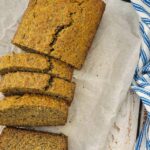 half sliced banana bread loaf on a parchment lined baking sheet next to a ramekin of chia seeds