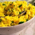 bowl of yellow rice with parsley and two spoons