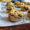 crab filled mushrooms on a parchment lined baking sheet garnished with fresh chopped parsley
