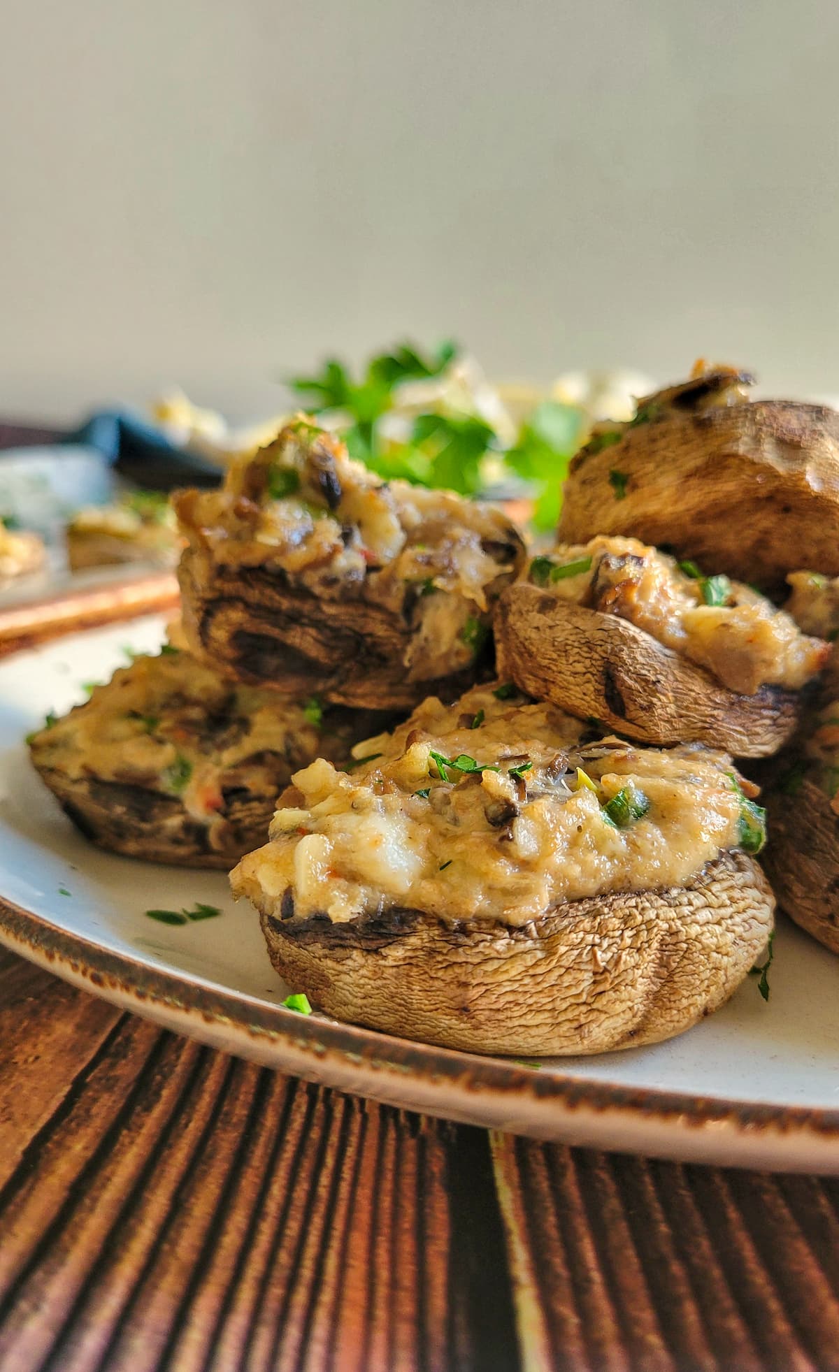 crab filled mushrooms garnished with fresh chopped parsley stacked on a plate
