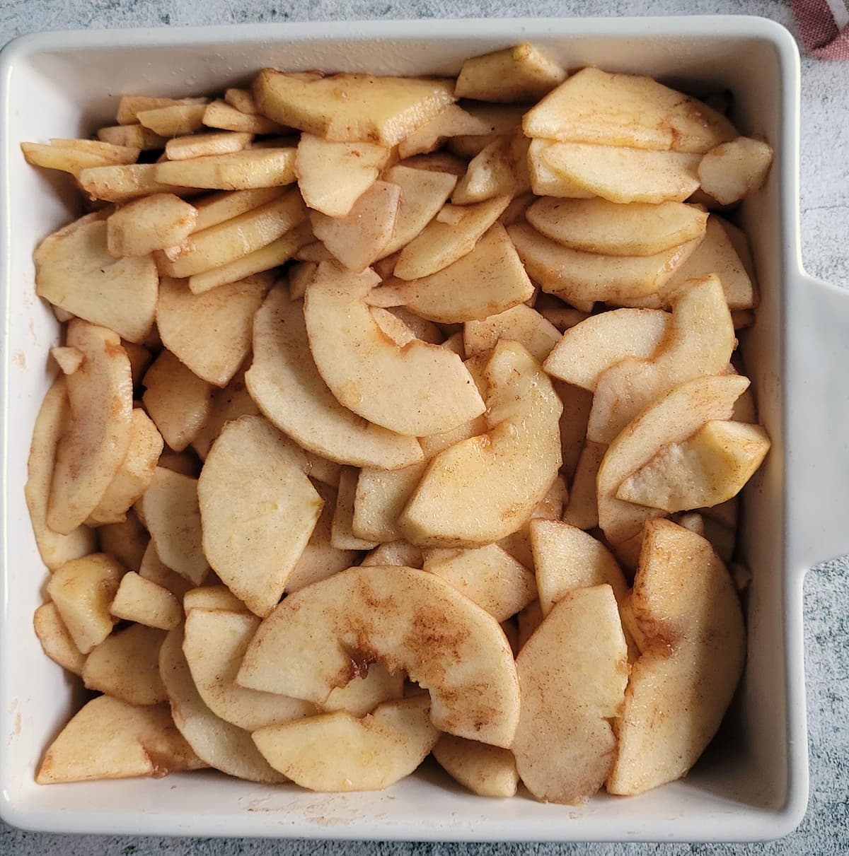 sliced apples with cinnamon in a square baking dish