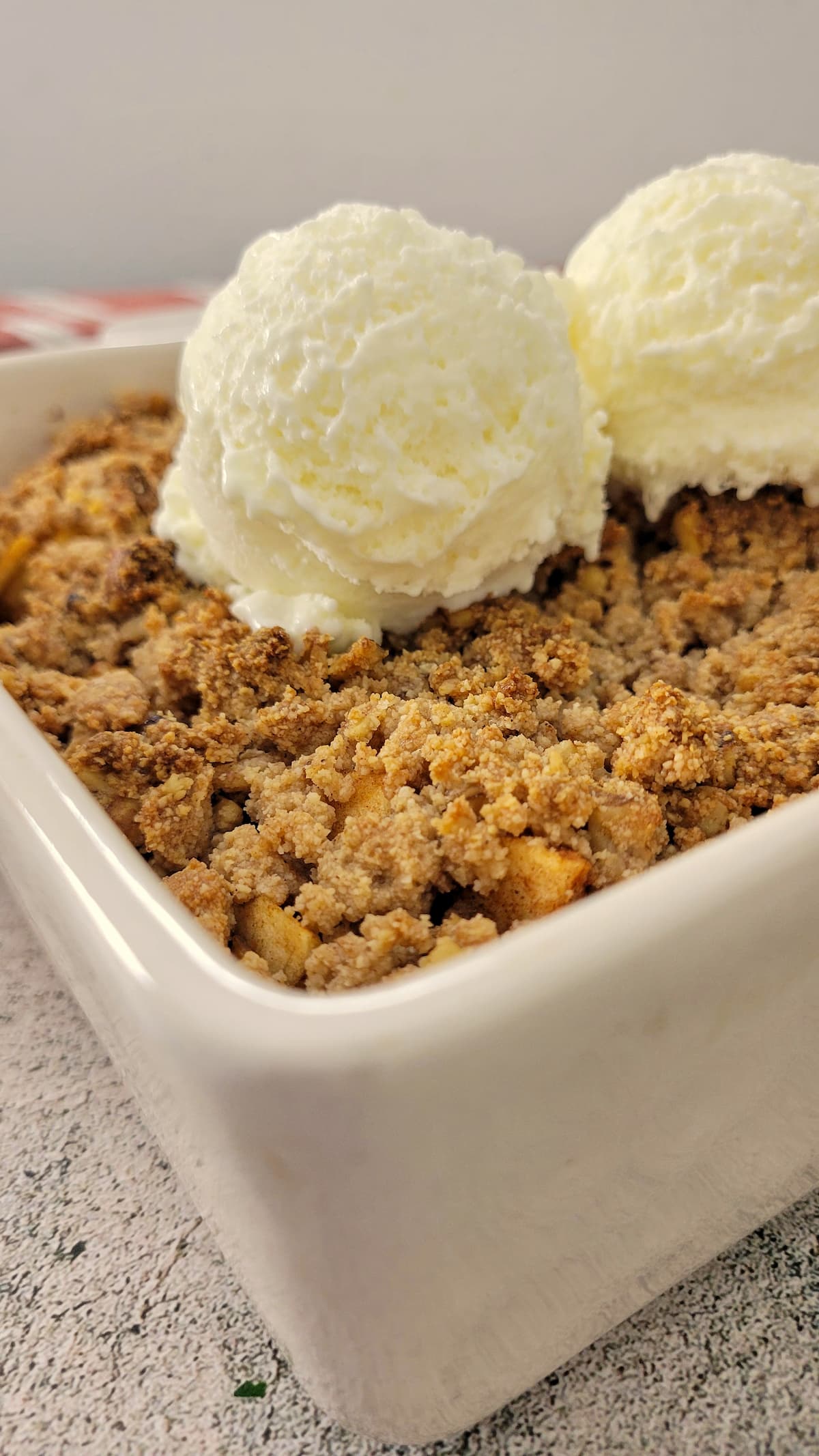 baked apple crisp in a baking dish with two scoops of ice cream