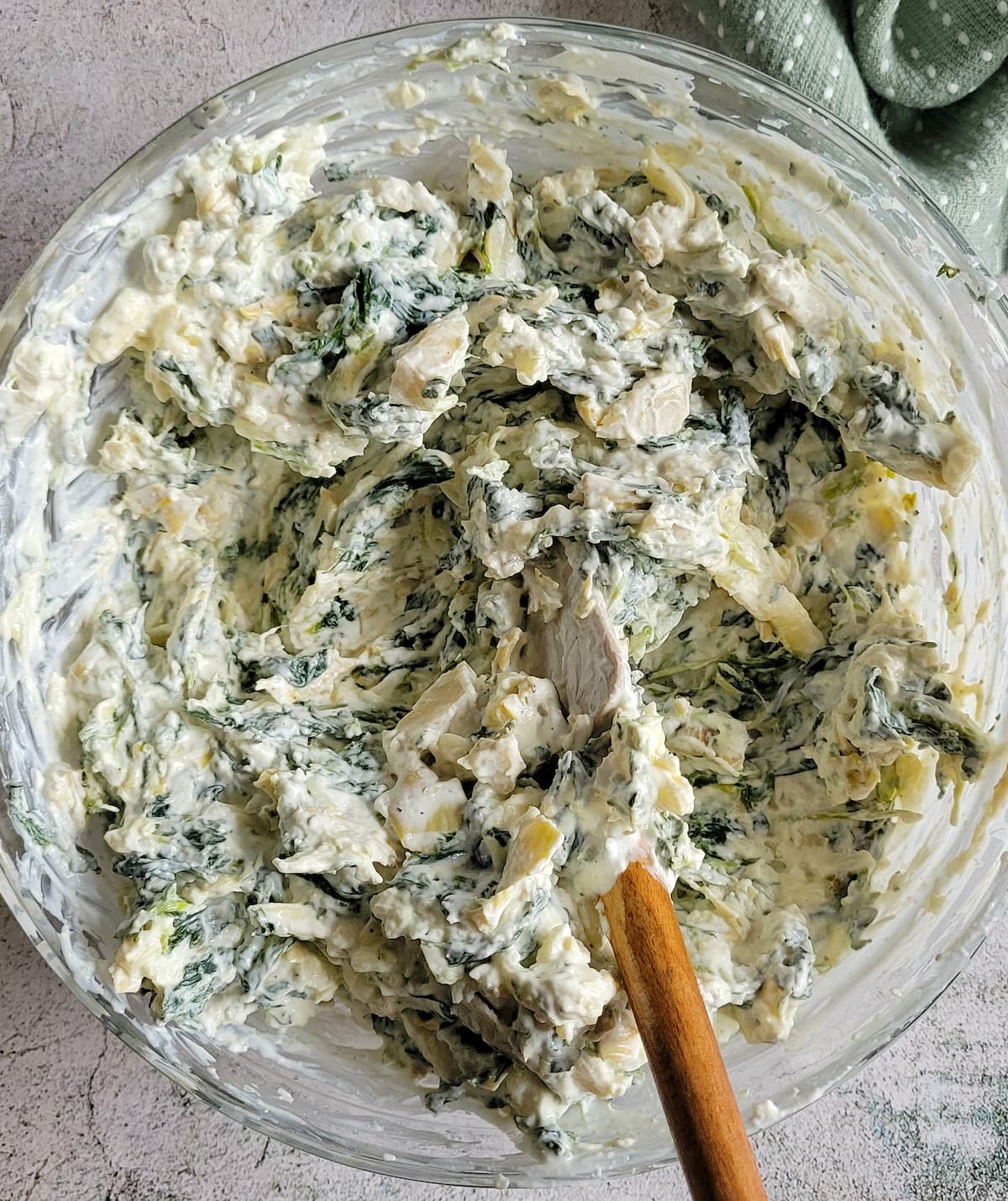 spinach and artichoke dip in a bowl with a rubber spatula