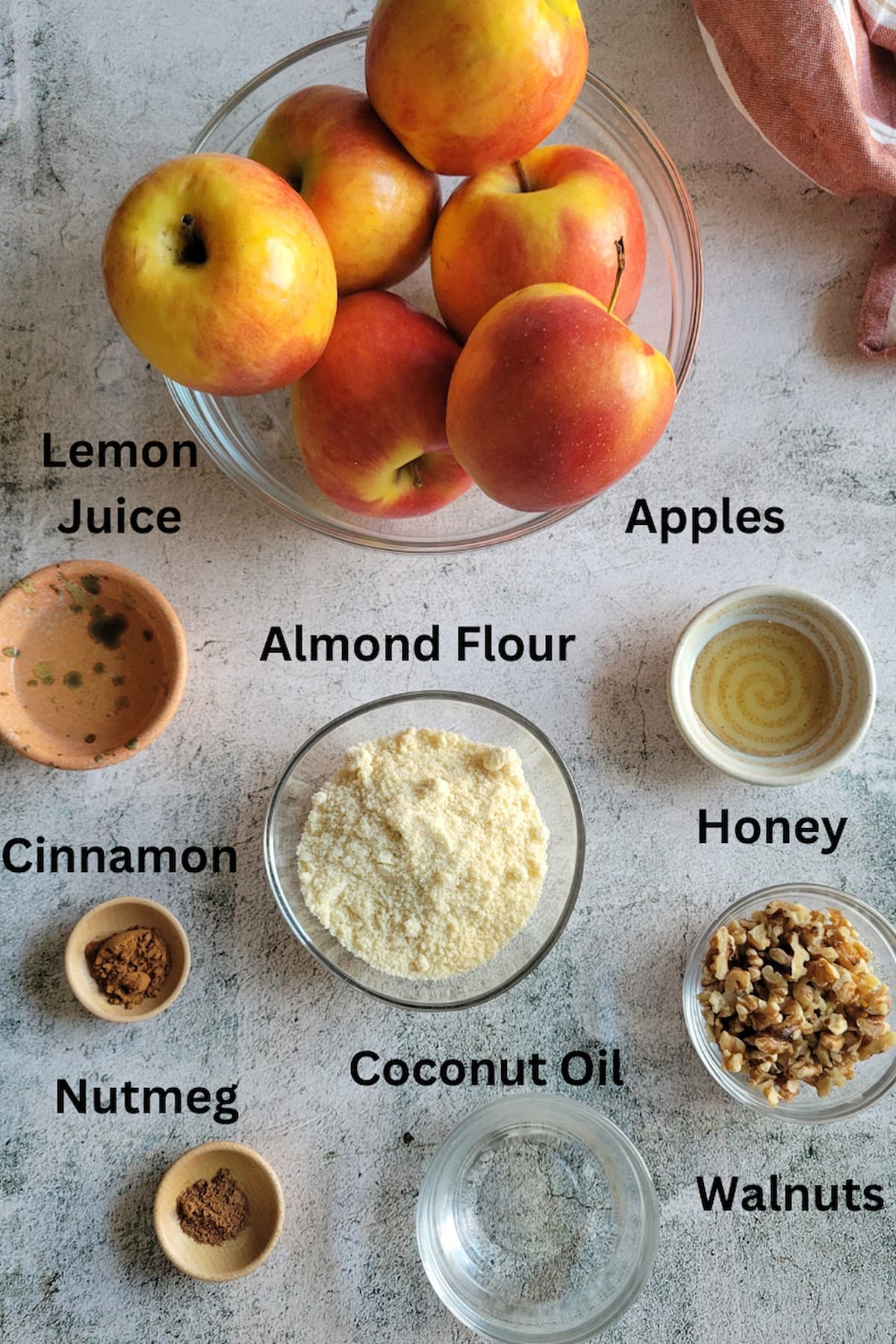 ingredients for recipe for apple crisp no oats - apples, almond flour, cinnamon, nutmeg, honey, lemon juice, walnuts, coconut oil