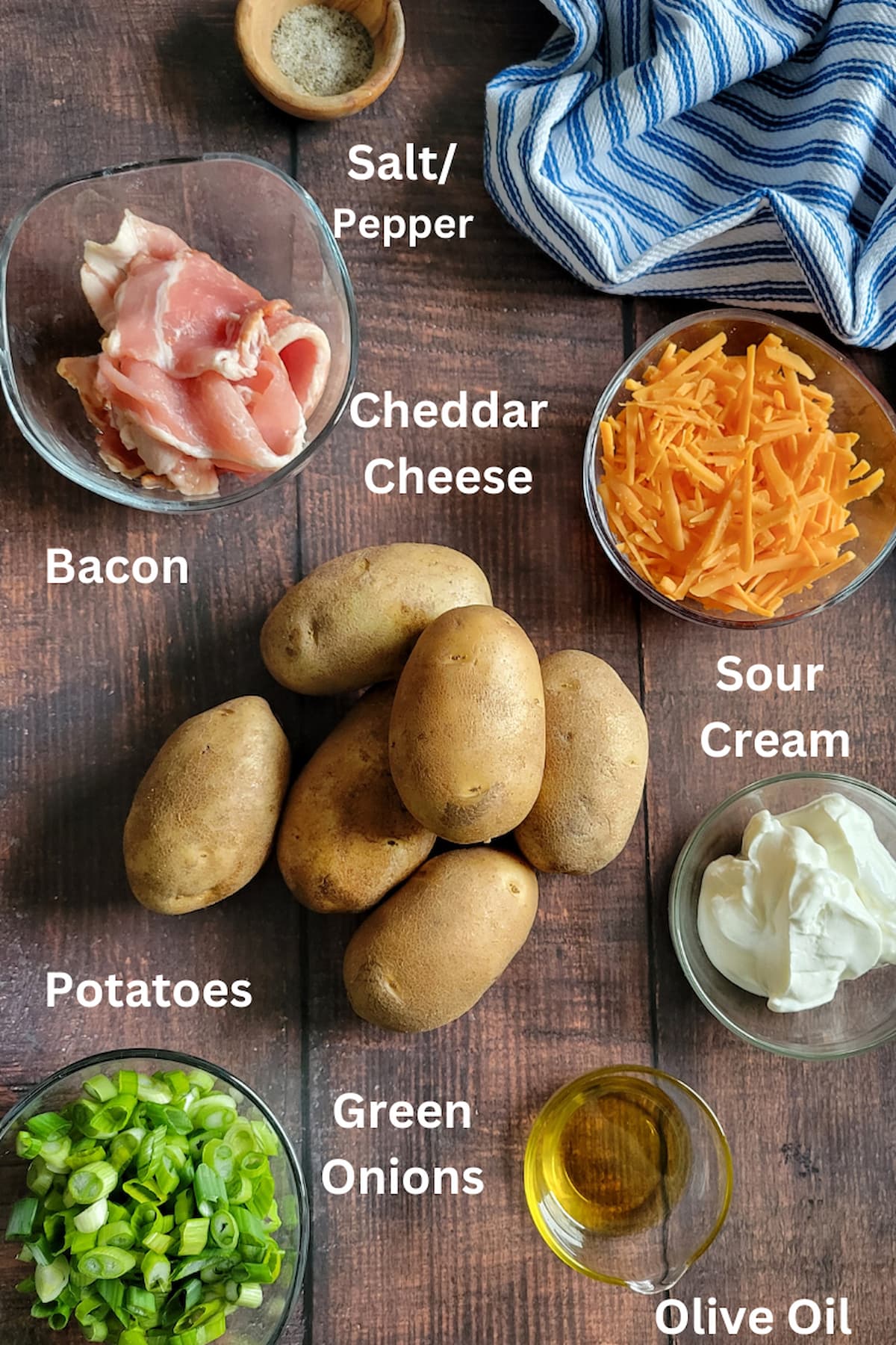 ingredients to make loaded potato skins - potatoes, bacon, green onions, cheddar cheese, salt/pepper, olive oil, sour cream