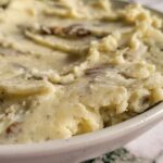 side view of a bowl mashed potatoes with a spoon in it