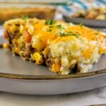 piece of ground beef shepherd's pie on a plate topped with chopped fresh parsley