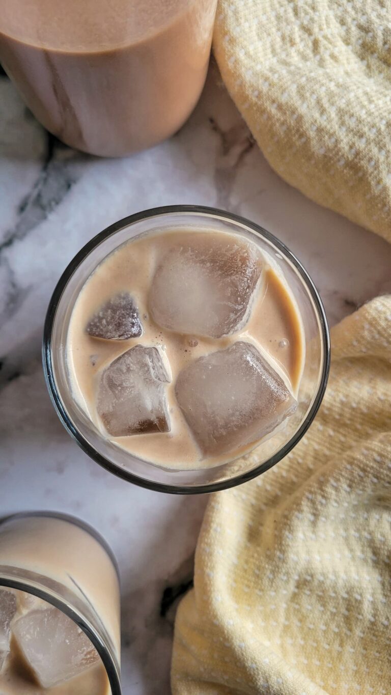 two glasses of baileys on the rocks next to a bottle of homemade baileys