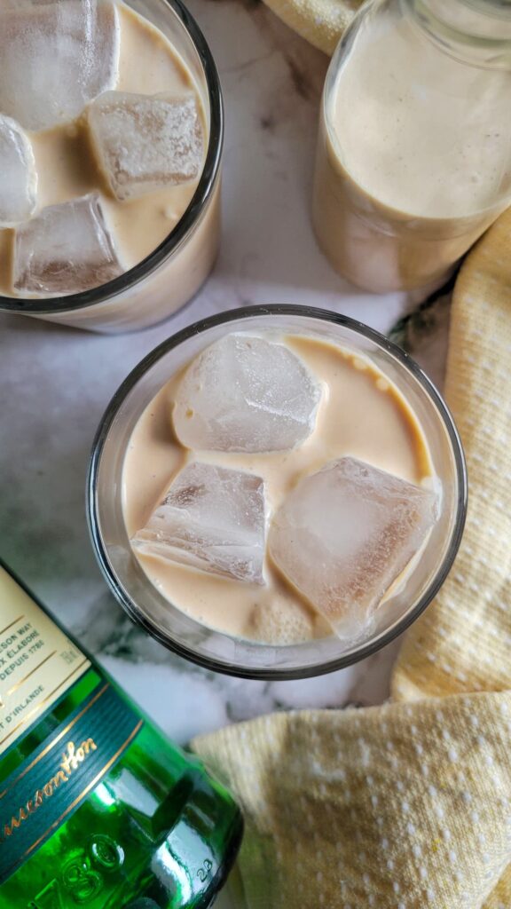2 glasses of baileys with ice next to a bottle of jameson and homemade baileys