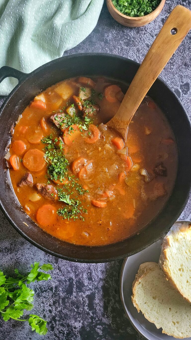 pot of irish beef stew with carrots and fresh chopped parsley, wooden spoon in the pot