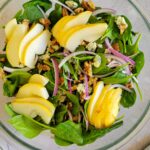 salad with pears, red onion, walnuts and blue cheese, jar of dressing in the background