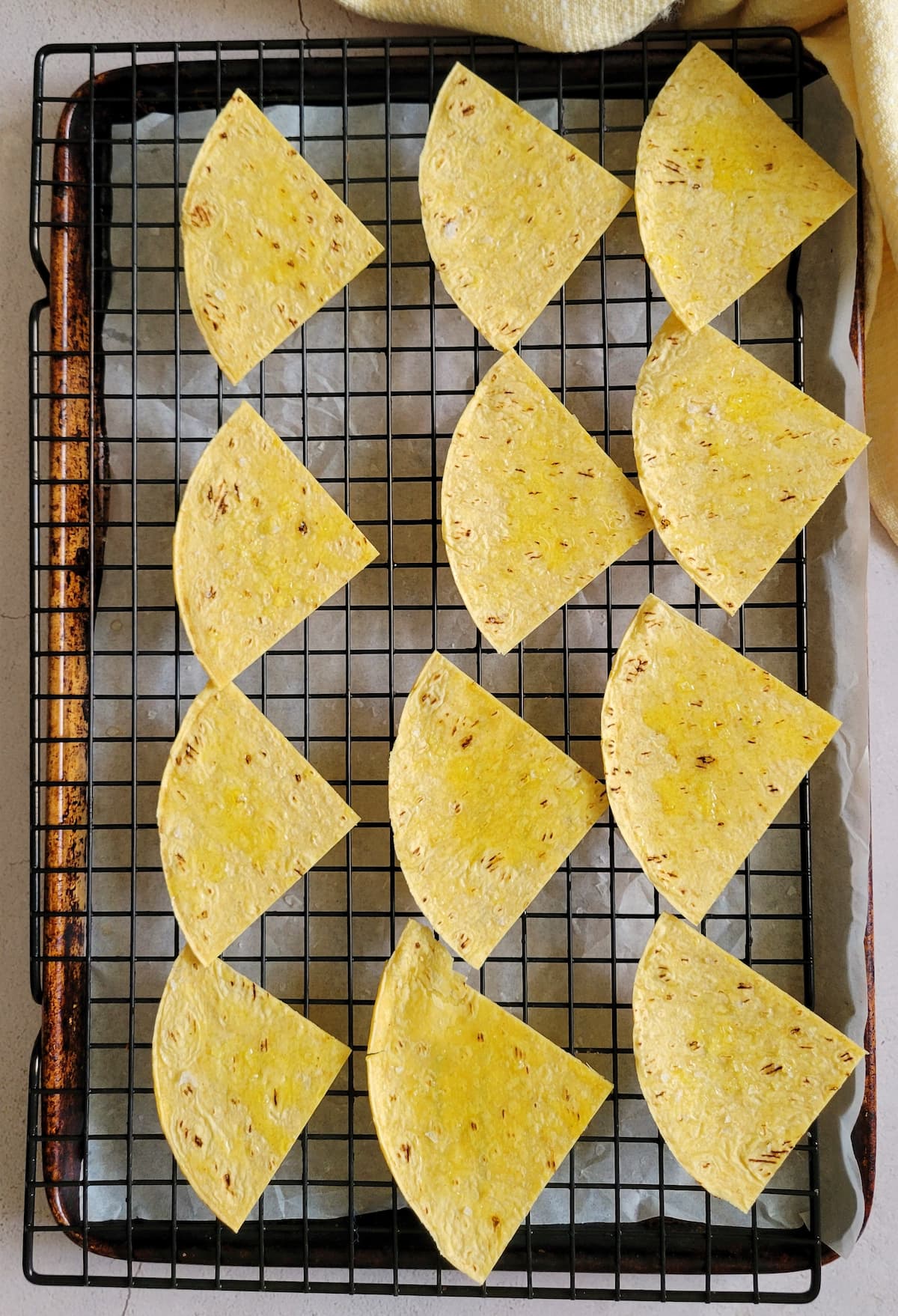 triangular corn tortilla chips on a wire rack and foil lined baking sheet