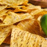 tray of tortilla chips with a bowl of salsa and lime