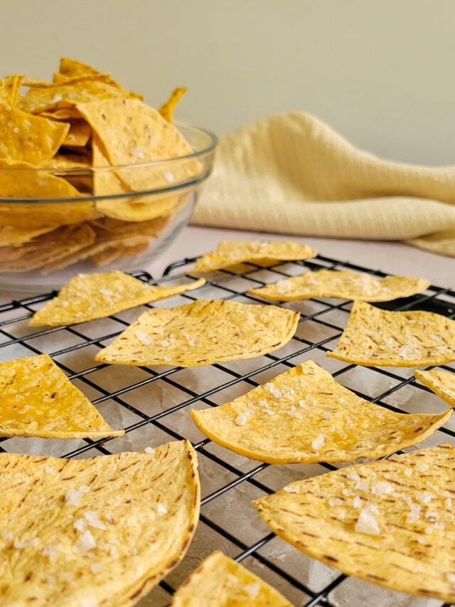 salted tortilla chips on a wire rack, bowl of more chips in the background