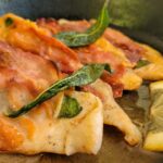 chicken saltimbocca in a cast iron skillet with lemon and fried sage
