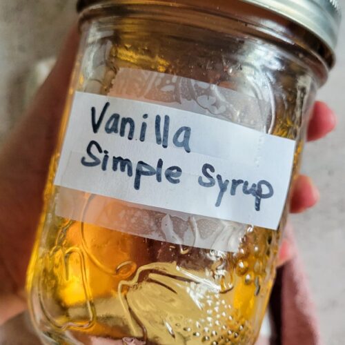 hands holding a closed jar of vanilla simple syrup
