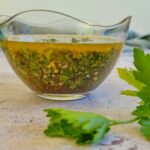 chimichurri in a bowl next to some parsley