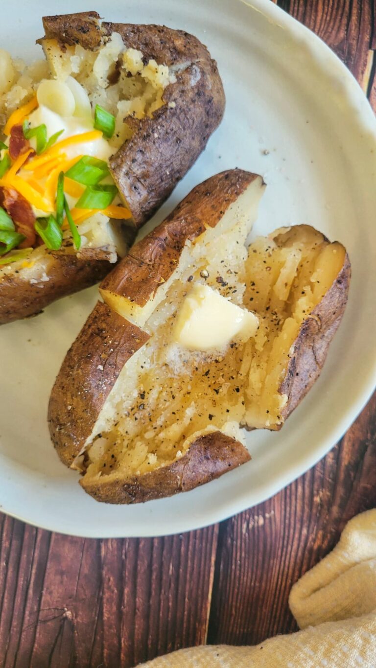 two baked potatoes on a plate, one loaded, and one with butter, salt and pepper