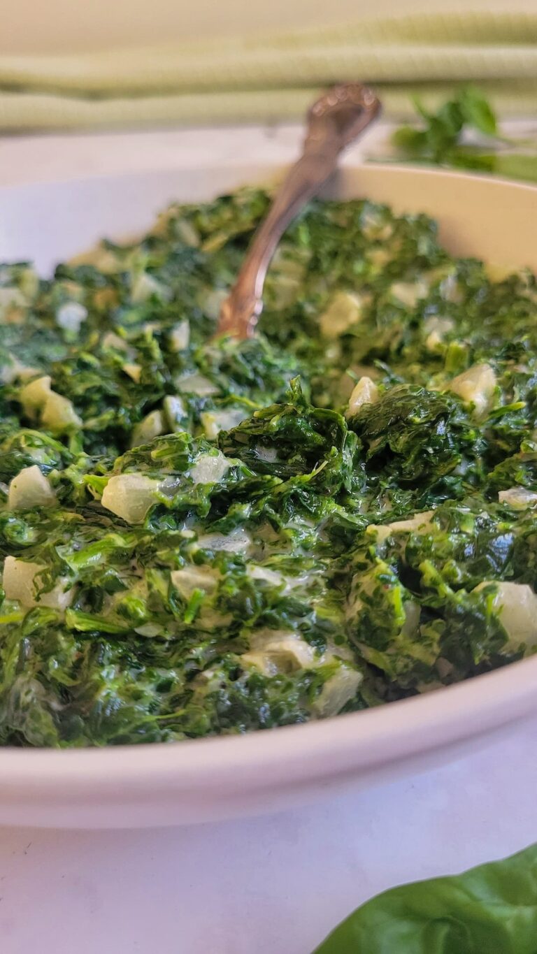creamed spinach in a bowl with onions and a spoon