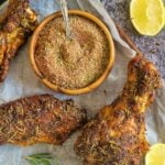 cooked turkey wings on a parchment lined baking sheet with lemon slices, rosemary, and a bowl of spices with a spoon in it
