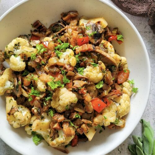 cauliflower in a bowl with red peppers, mushrooms, pecans, bacon, and fresh herbs