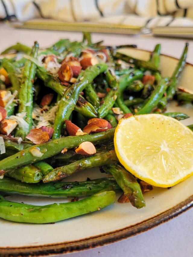 grilled green beans on a plate with almonds, parmesan, and lemon