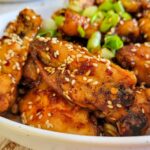 asian hot wings in a bowl with sesame seeds and green onions