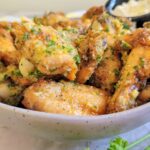 garlic and parmesan chicken wings garnished with fresh chopped parsley in a bowl with a creamy sauce
