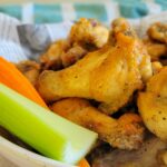 bowl of seasoned cooked wings with a carrot and celery stick