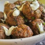 bowl of meatballs drizzled with white sauce