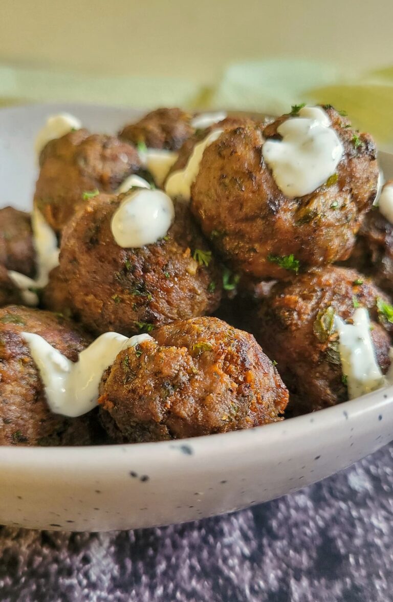 bowl of meatballs drizzled with white sauce
