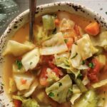cabbage soup with carrots, diced tomatoes, cleery, green beans, and chopped herbs