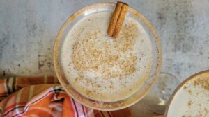 rimmed pumpkin spice martini with cinnamon stick and powdered cinnamon.