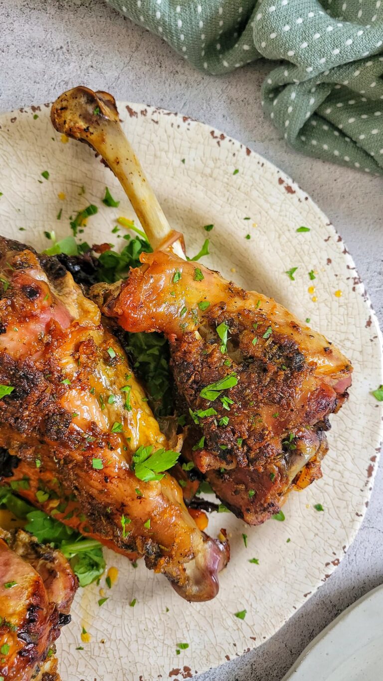 3 roasted seasoned turkey drumsticks on a plate seasoned with fresh chopped parsley