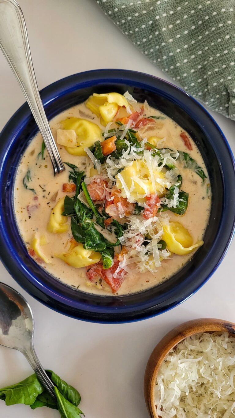 bowl of tortellini soup with cream, spinach, tomatoes, and parmesan cheese