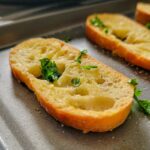 garlic crostini on a tray, more on a plate in the background