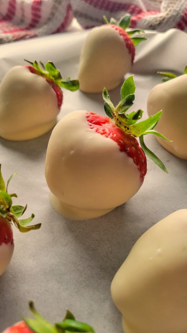 white chocolate covered strawberries on a parchment lined baking sheet
