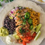 burrito bowl with chicken, black beans, corn, lime, cherry tomatoes, red onion, guac, greek yogurt
