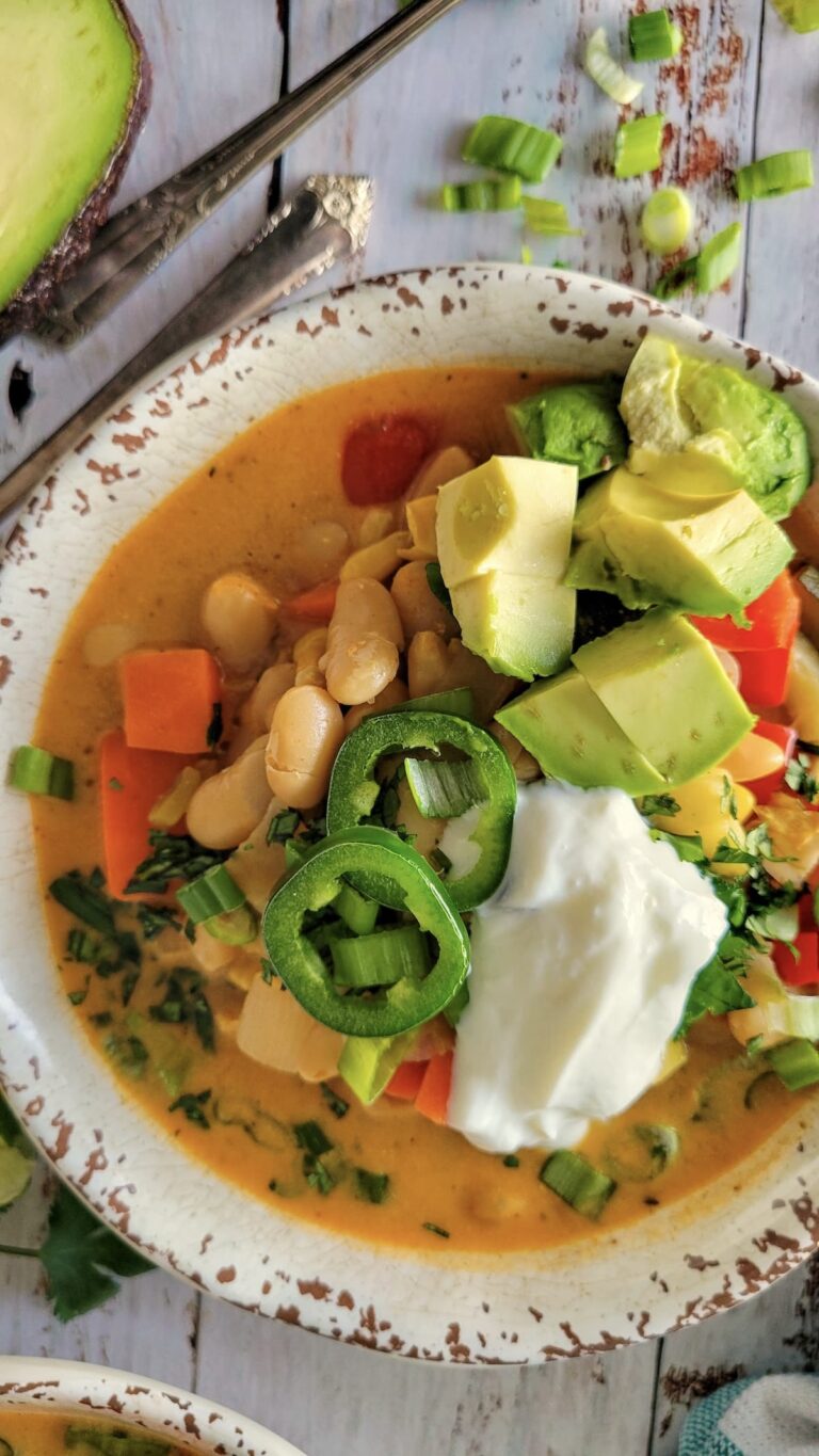 bowl of vegan white bean chili topped with greek yogurt, sliced jalapenos, cilantro, and avocado