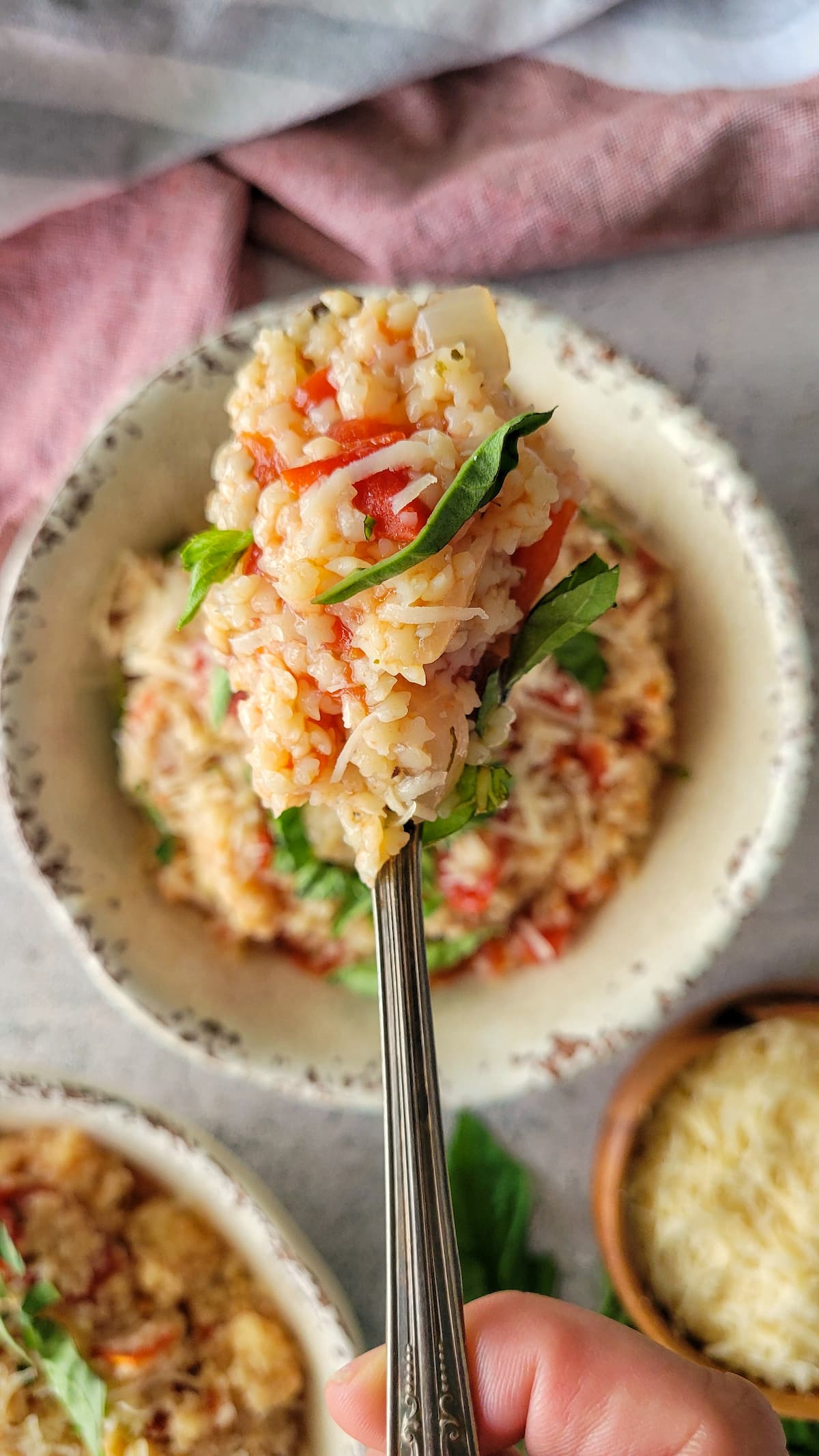spoonful of tomato pastina with basil over a bowl with more