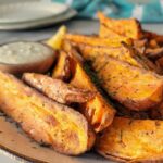 air fryer sweet potato wedges on a plate with a creamy dipping sauce on a remekin