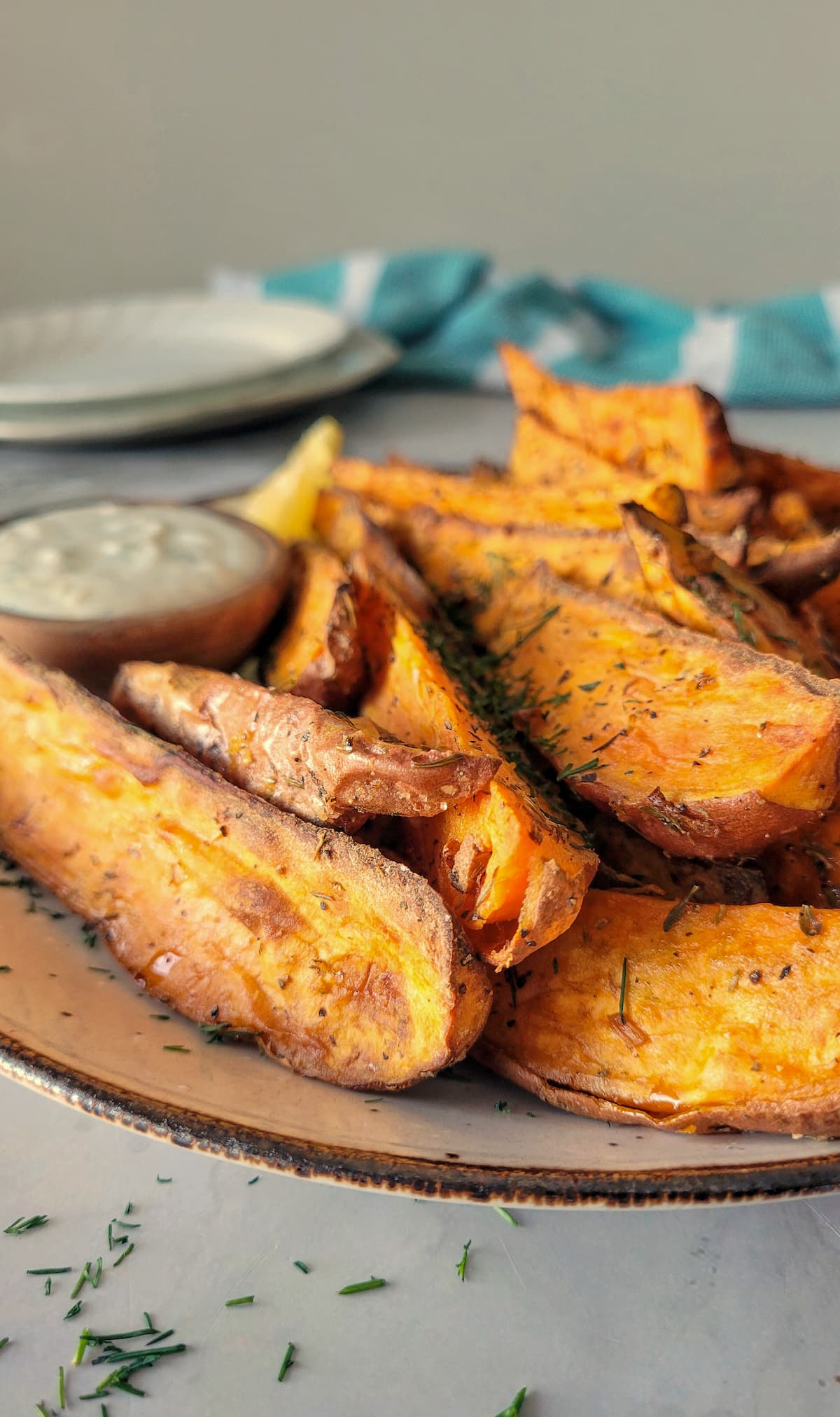 air fryer sweet potato wedges on a plate with a creamy dipping sauce on a remekin
